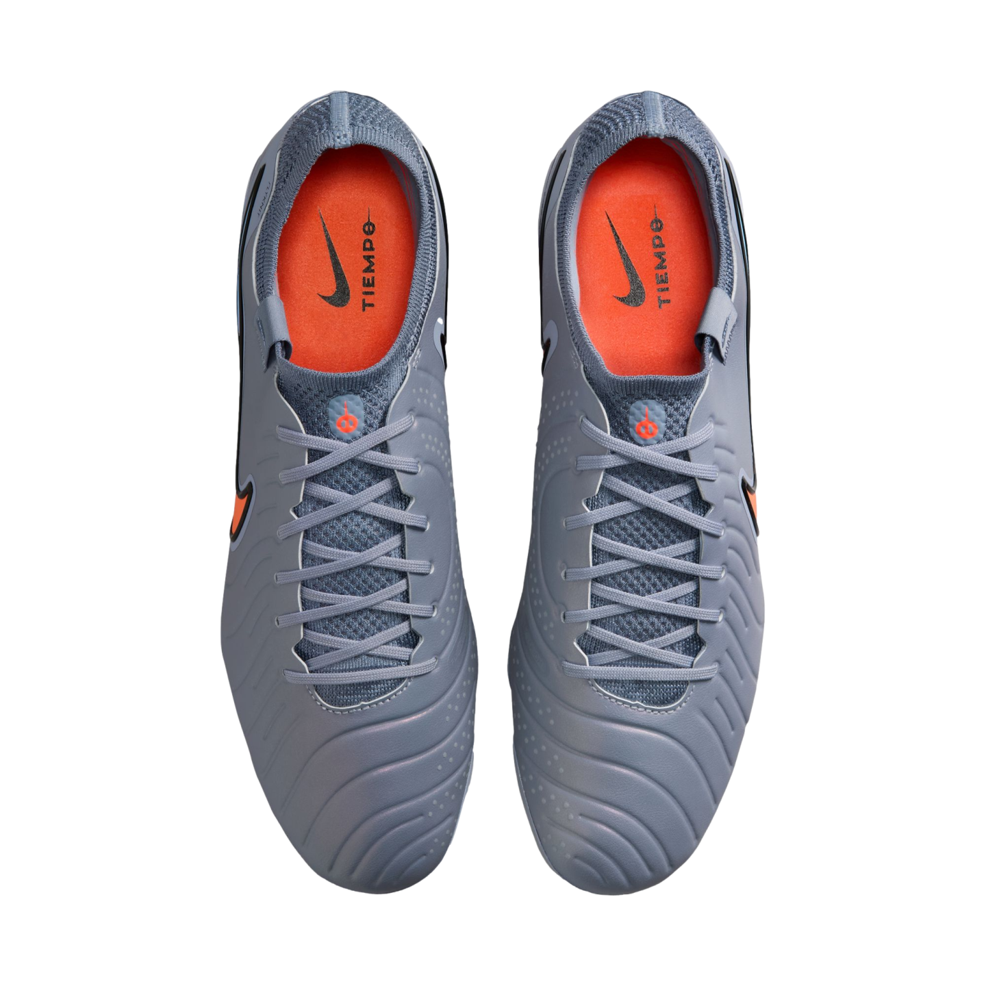 Top-down view of grey Nike Tiempo soccer cleats with bright orange interiors and grey laces, shown against a black background.