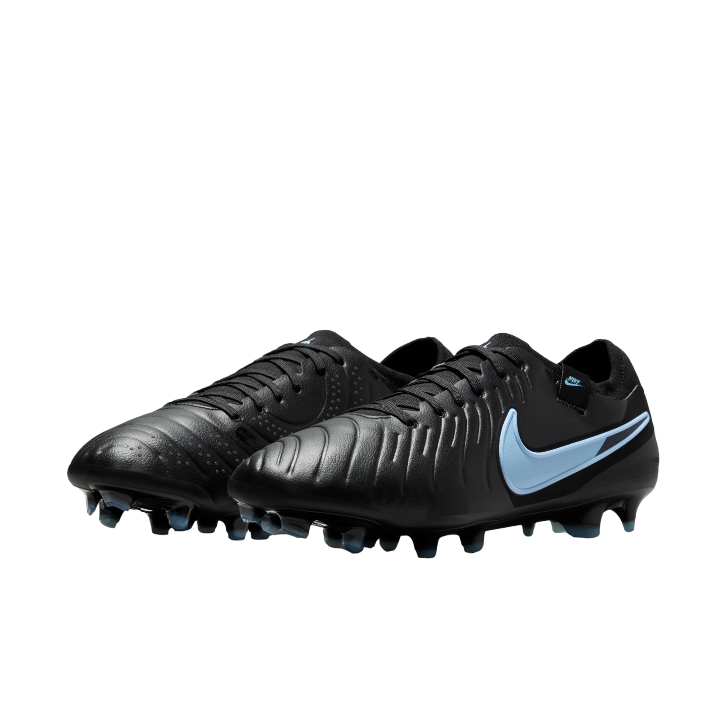 A pair of black Nike soccer cleats with light blue swoosh logos and textured uppers, positioned against a solid black background.