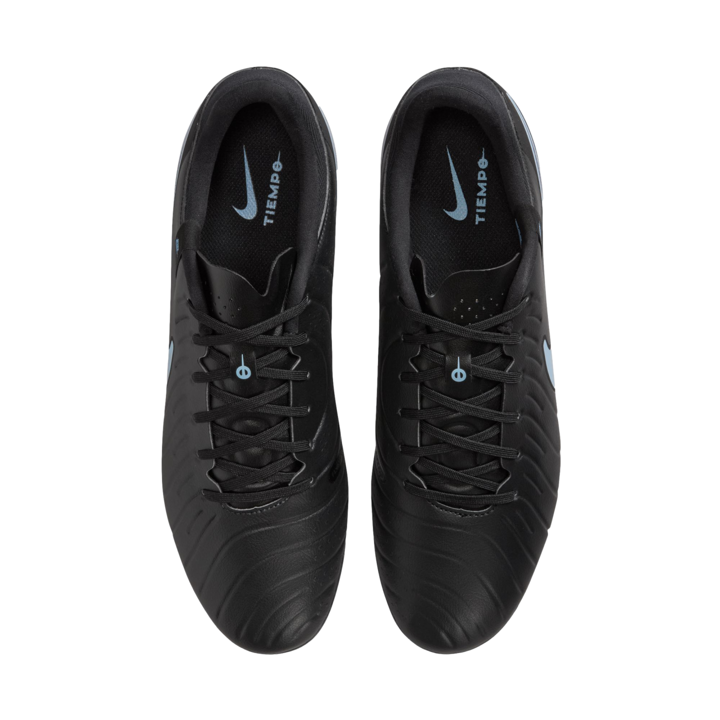 Overhead view of black Nike Tiempo soccer cleats on a black background, showing light blue logos on the inner soles.