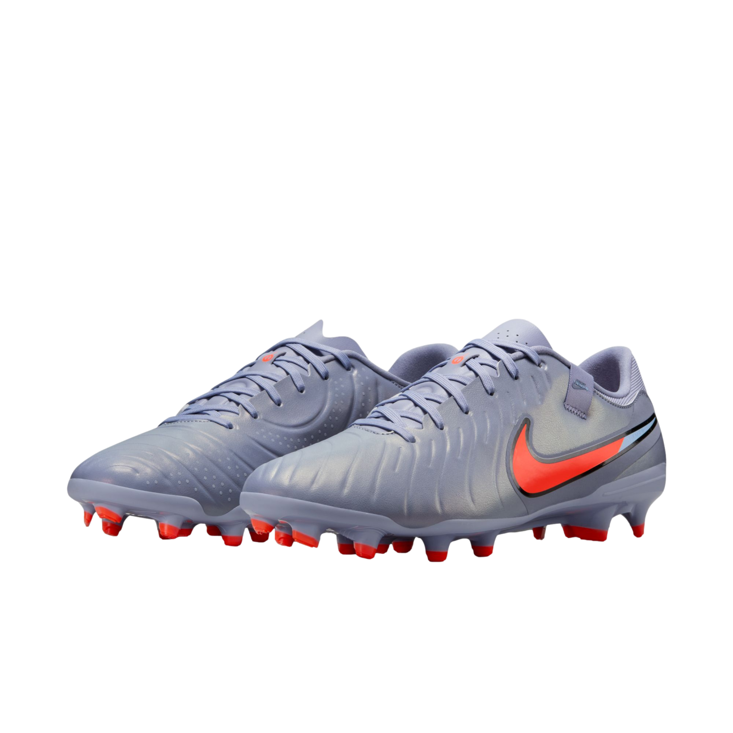 Lavender-grey Nike soccer cleats with a vibrant orange swoosh and orange-tipped studs, shown against a solid black background.