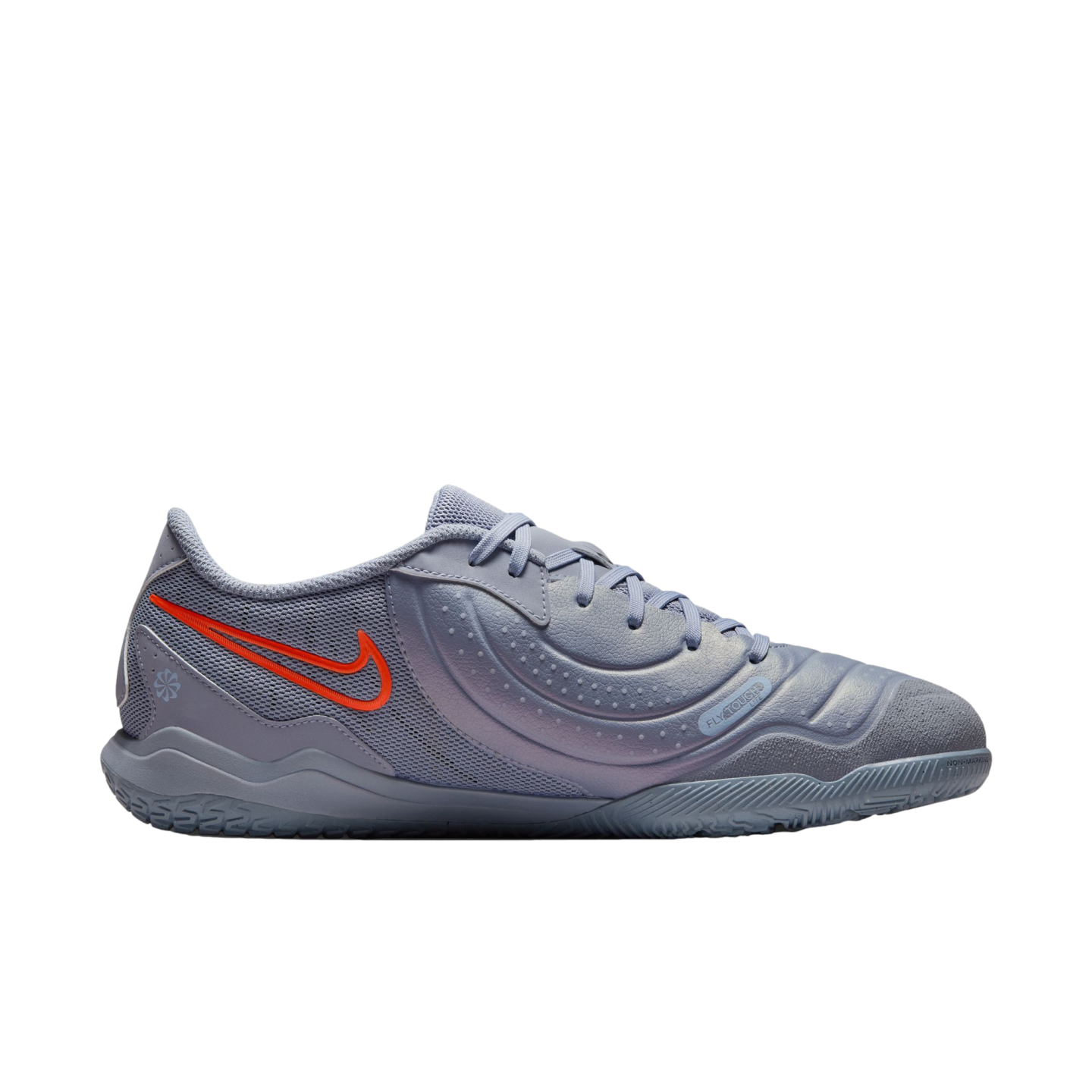 Profile view of a light purple Nike indoor soccer shoe with a bright orange swoosh, featuring a textured upper and flat sole, set against a black background.