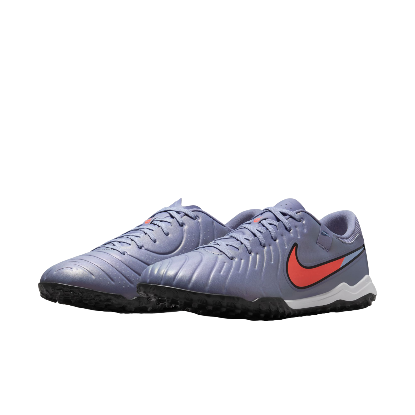 Lavender Nike turf soccer shoes with an orange swoosh and black knobby outsoles, set against a black background.