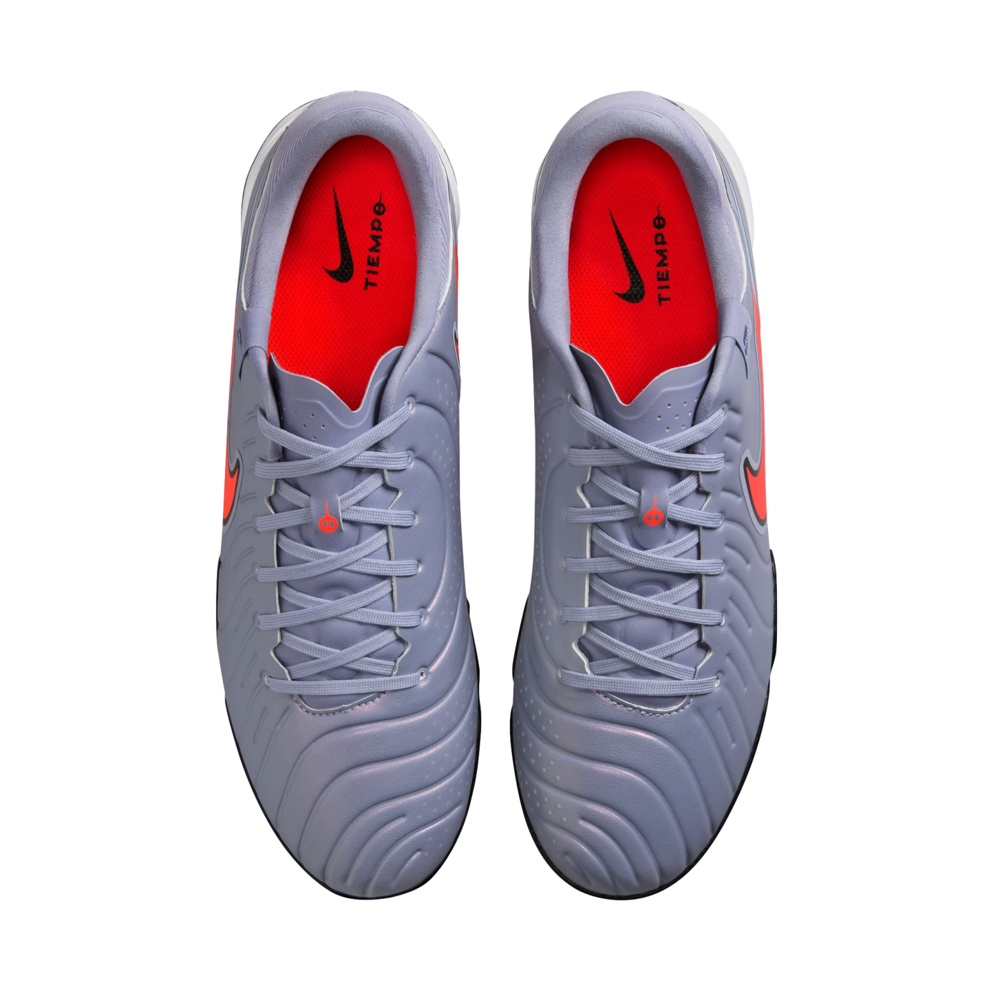 Top-down view of a pair of light purple Nike Tiempo soccer cleats with bright red insoles and orange accents, centered on a black background.