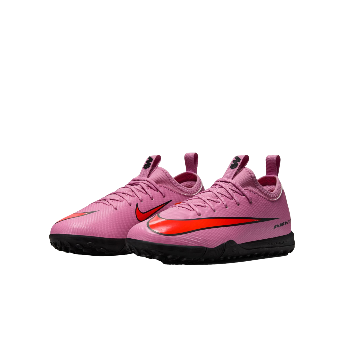 A pair of pink Nike turf soccer shoes with bright orange swooshes and black soles, shown against a black background.