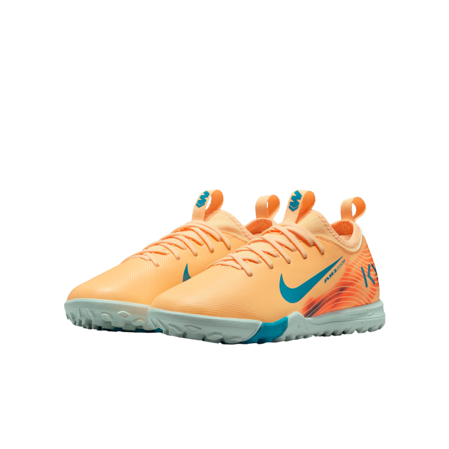 A pair of peach-colored Nike Air Zoom turf soccer shoes with teal accents and a light grey studded sole.