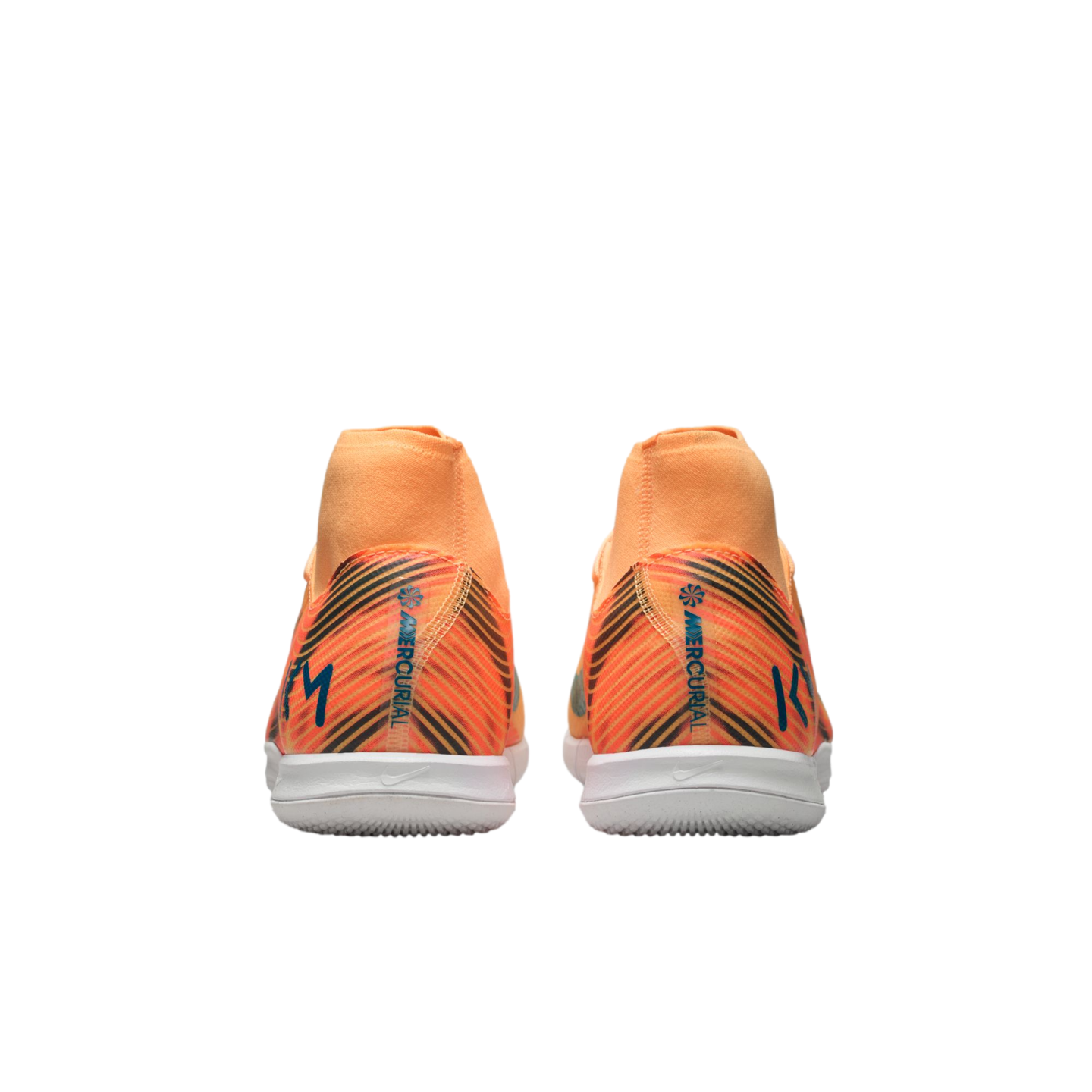 Rear view of orange Nike Mercurial indoor soccer shoes featuring black diagonal stripes, white soles, and high collars against a black background.