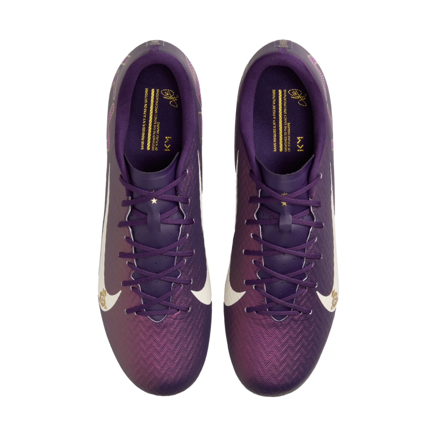Top-down view of purple Nike soccer cleats with a textured gradient upper, white swooshes, and gold branding on the insoles against a white background.