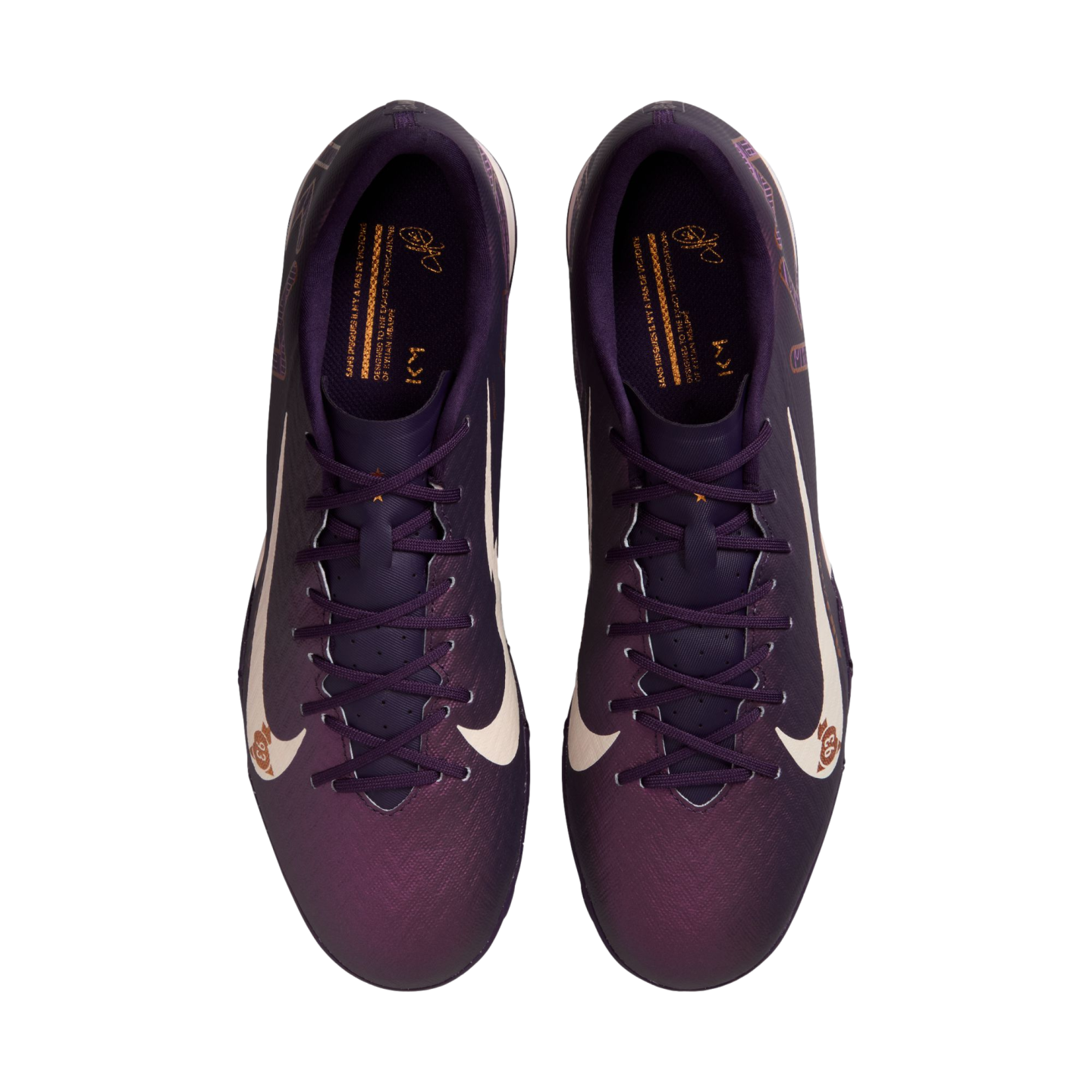 Top-down view of purple Nike soccer cleats with large white swooshes and gold interior accents on a white background.