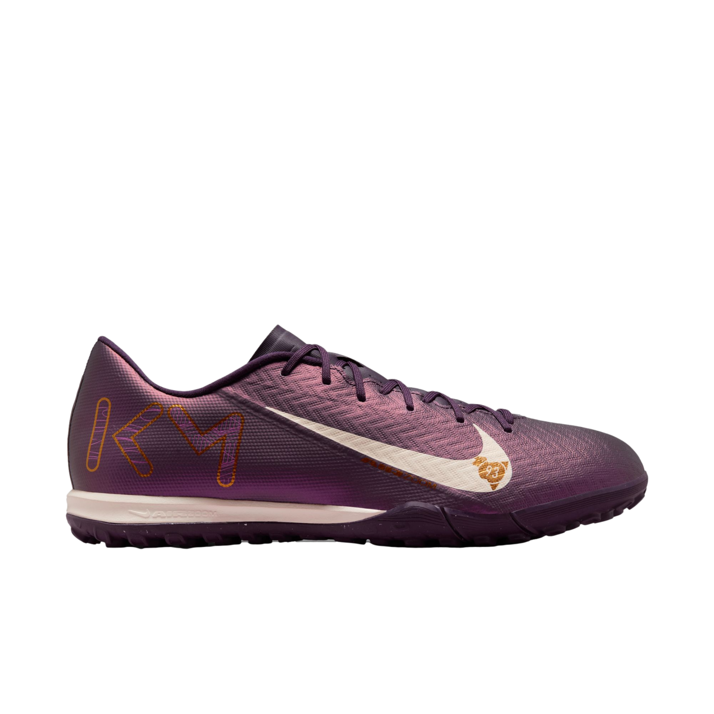 Side view of an iridescent purple Nike Mercurial turf soccer shoe featuring a large white Swoosh and gold "KM" branding on the heel.
