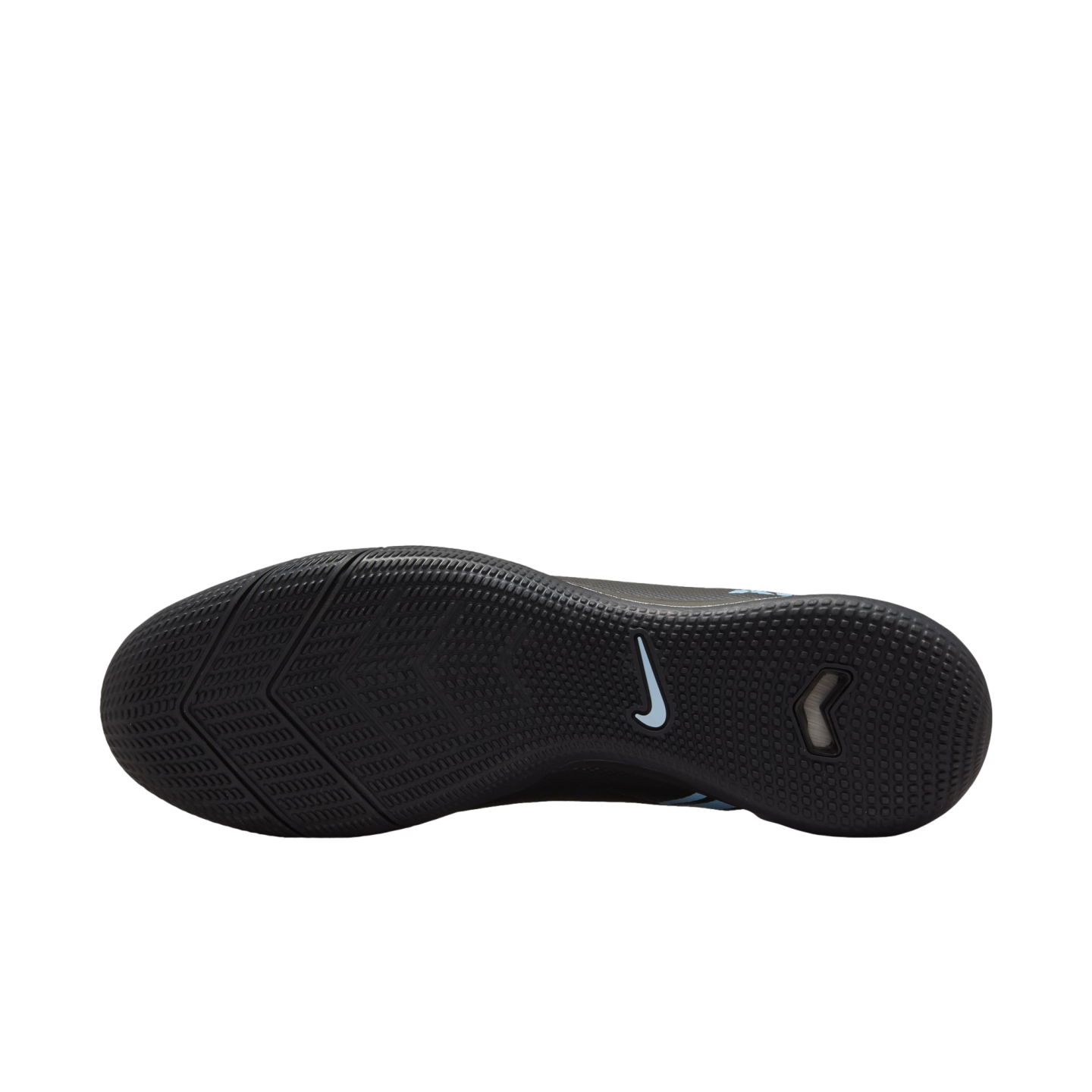 The textured black outsole of a Nike indoor soccer shoe features an intricate tread pattern and a light blue swoosh logo.