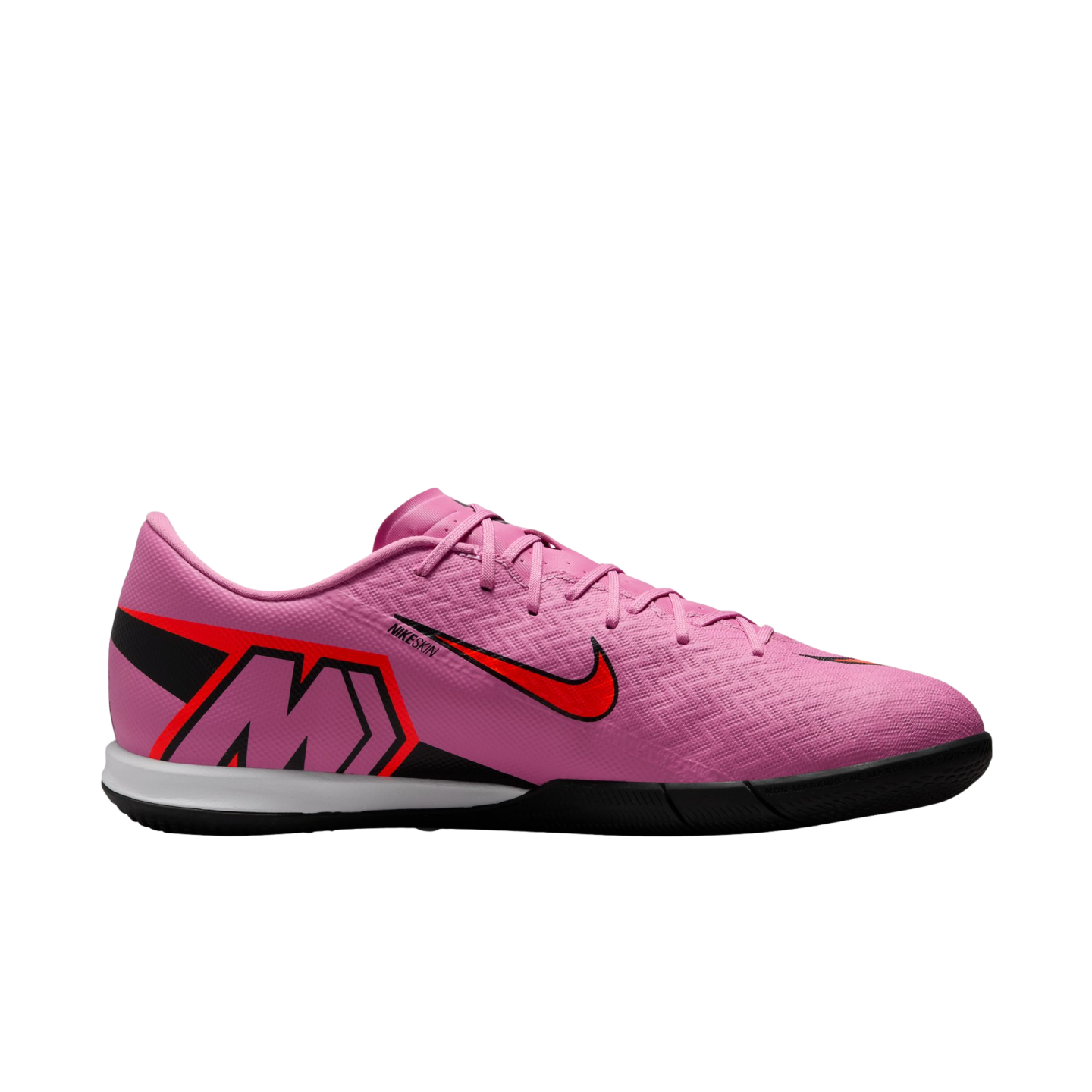 Profile view of a pink Nike indoor soccer shoe with red and black accents and a large "M" logo, isolated on a black background.