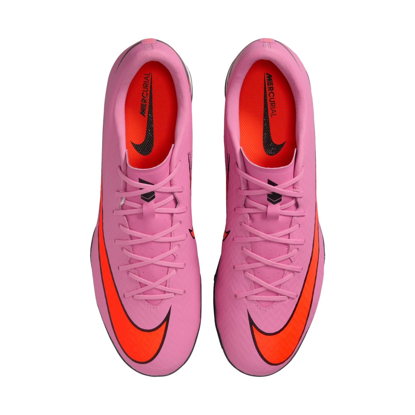 A top-down view of a pair of pink Nike Mercurial soccer cleats with bright orange Nike swooshes and orange interiors, centered on a solid black background.
