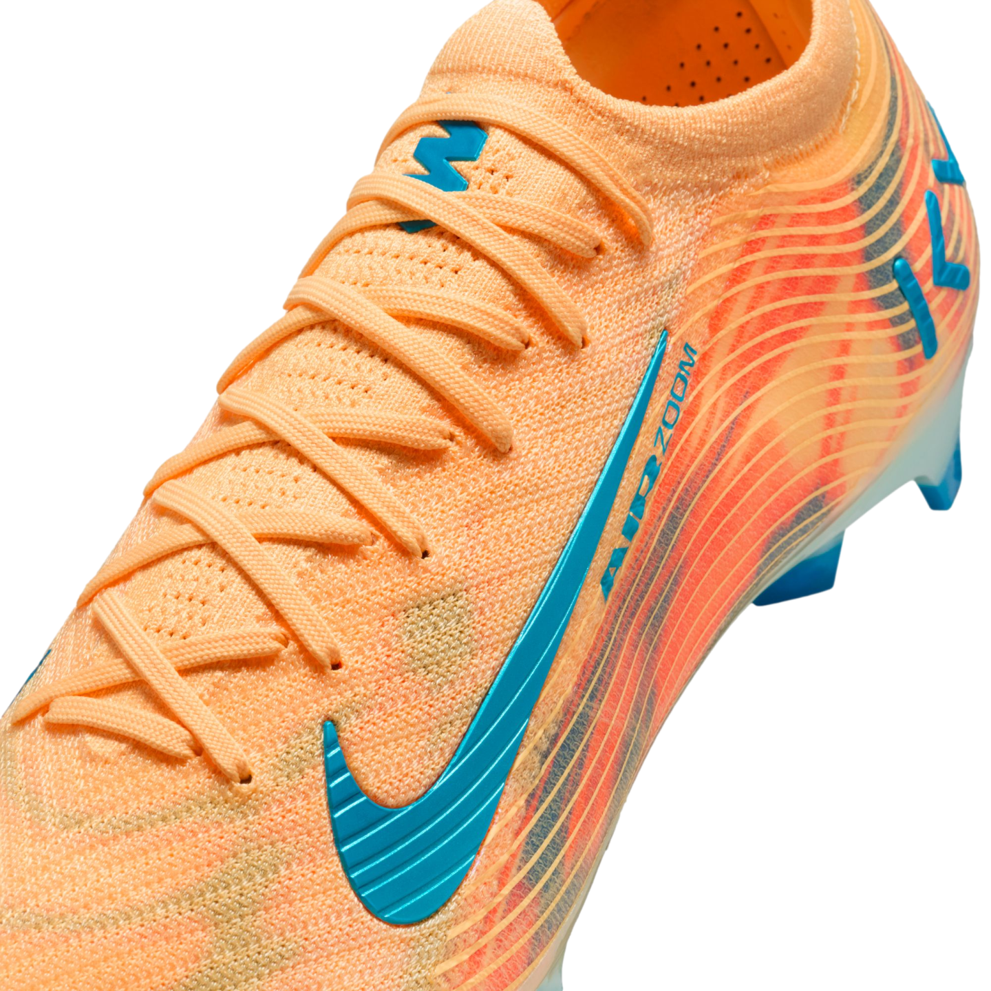Close-up of an orange Nike soccer cleat with teal accents, featuring a textured knit upper, orange laces, and AIR ZOOM branding.