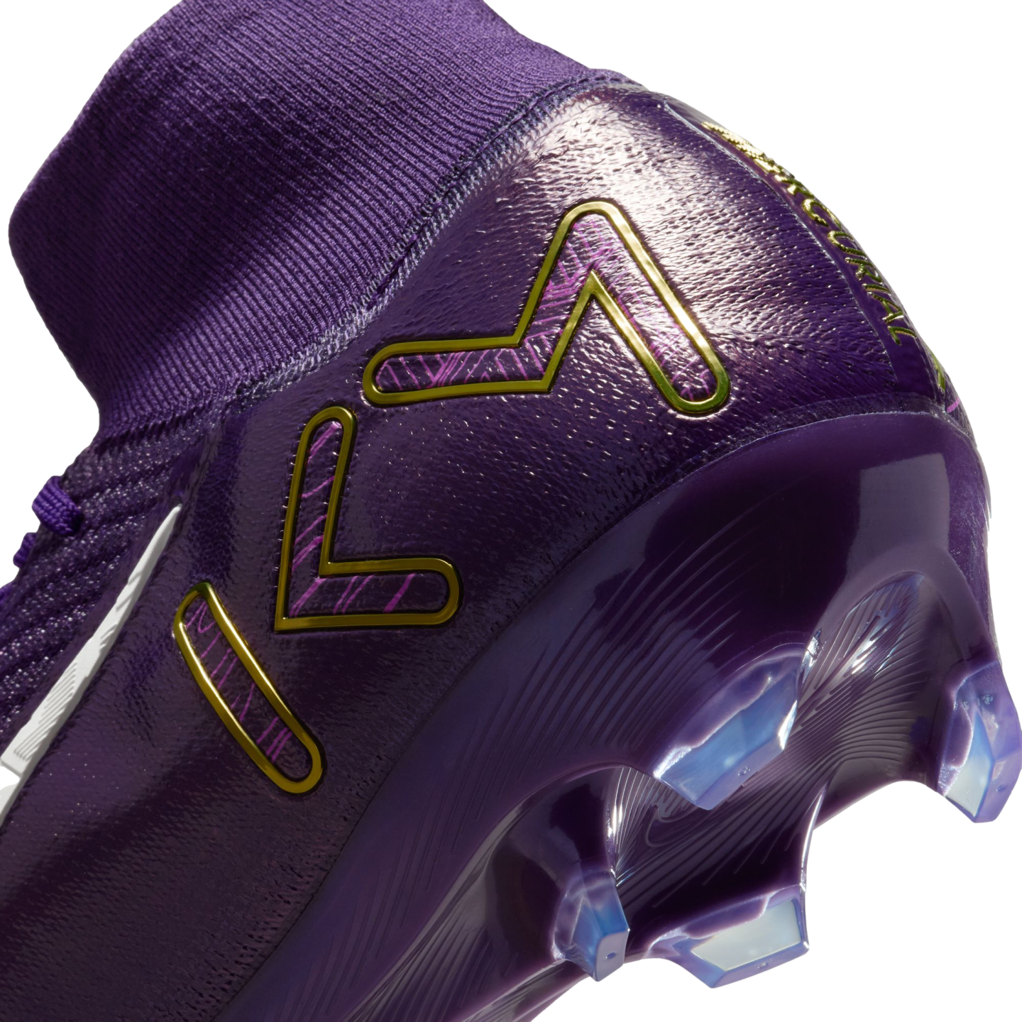 Close-up of a purple Nike Mercurial soccer cleat with a gold KM logo on the heel, featuring a knit ankle collar and clear cleats on the soleplate.