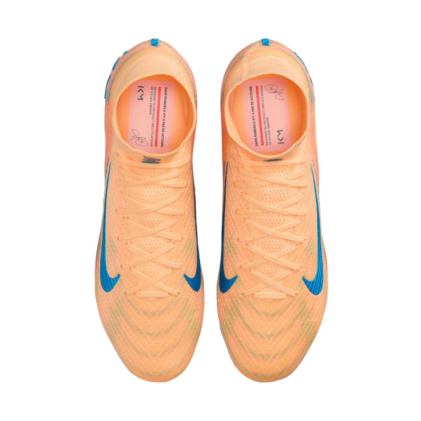Top-down view of a pair of bright orange Nike soccer cleats with blue swooshes, displayed against a solid black background.