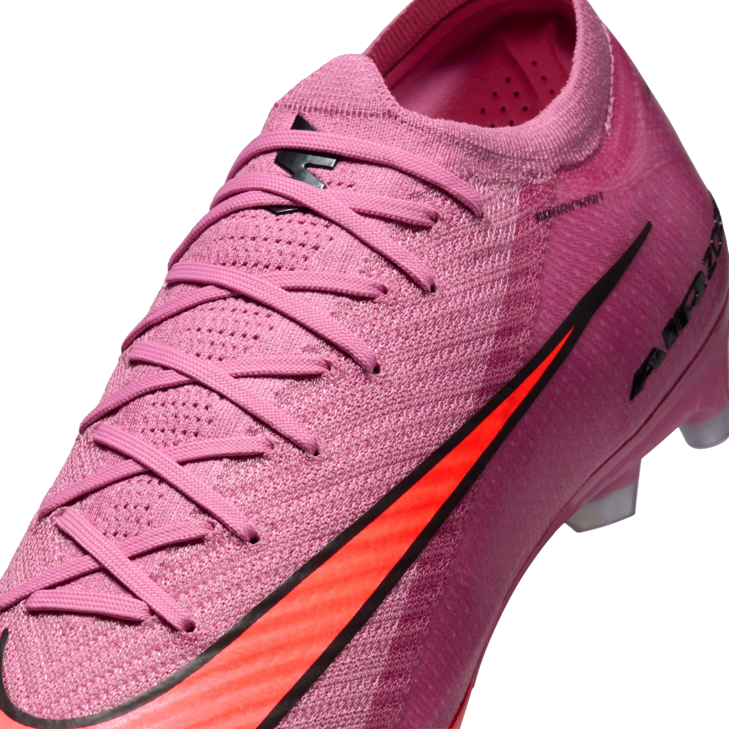 Close-up of a pink Nike soccer cleat featuring a textured knit upper, matching pink laces, and a vibrant orange swoosh logo with black trim.