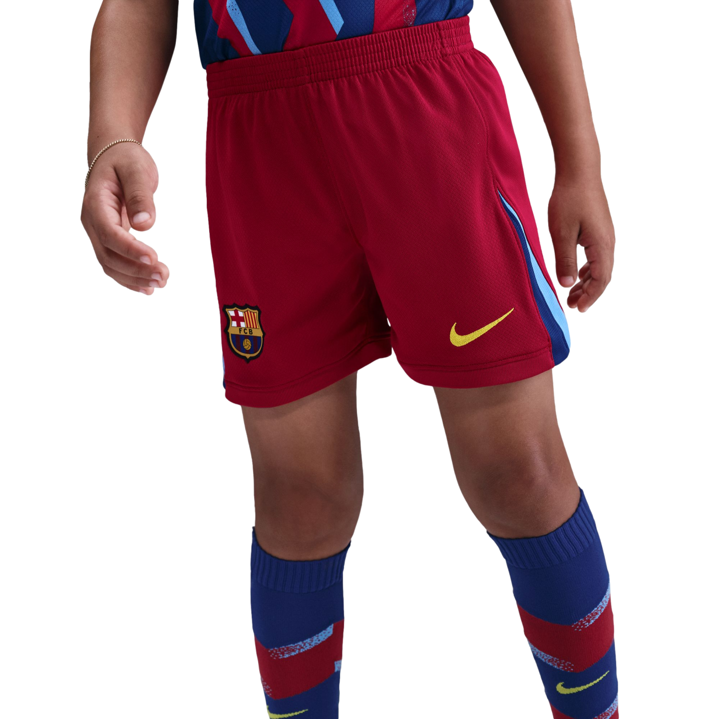 A person wearing red FC Barcelona football shorts with a yellow Nike swoosh and team crest, paired with blue and red patterned knee-high socks.