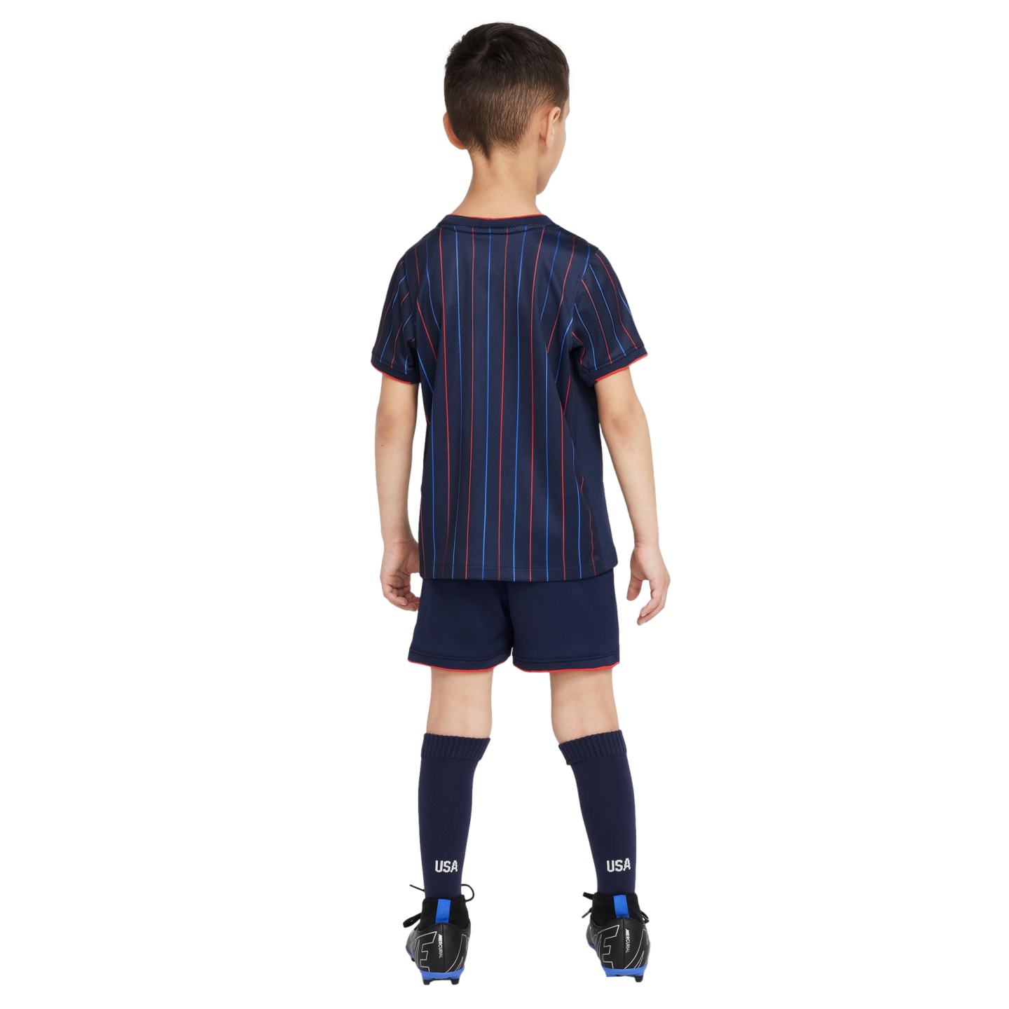 Rear view of a boy in a navy blue USA soccer kit with red and blue pinstripes, matching shorts with red trim, navy socks labeled "USA," and black soccer cleats.