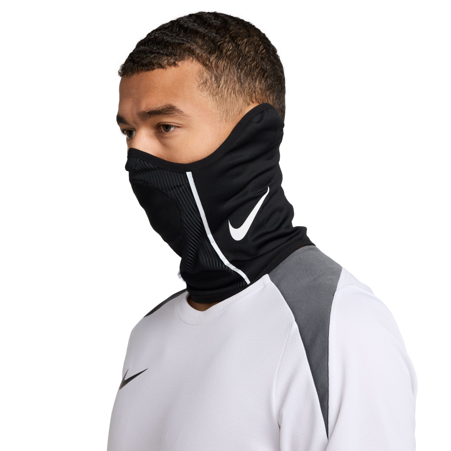 Man wearing a black Nike neck gaiter with a white swoosh logo and a white athletic long-sleeve shirt against a black background.
