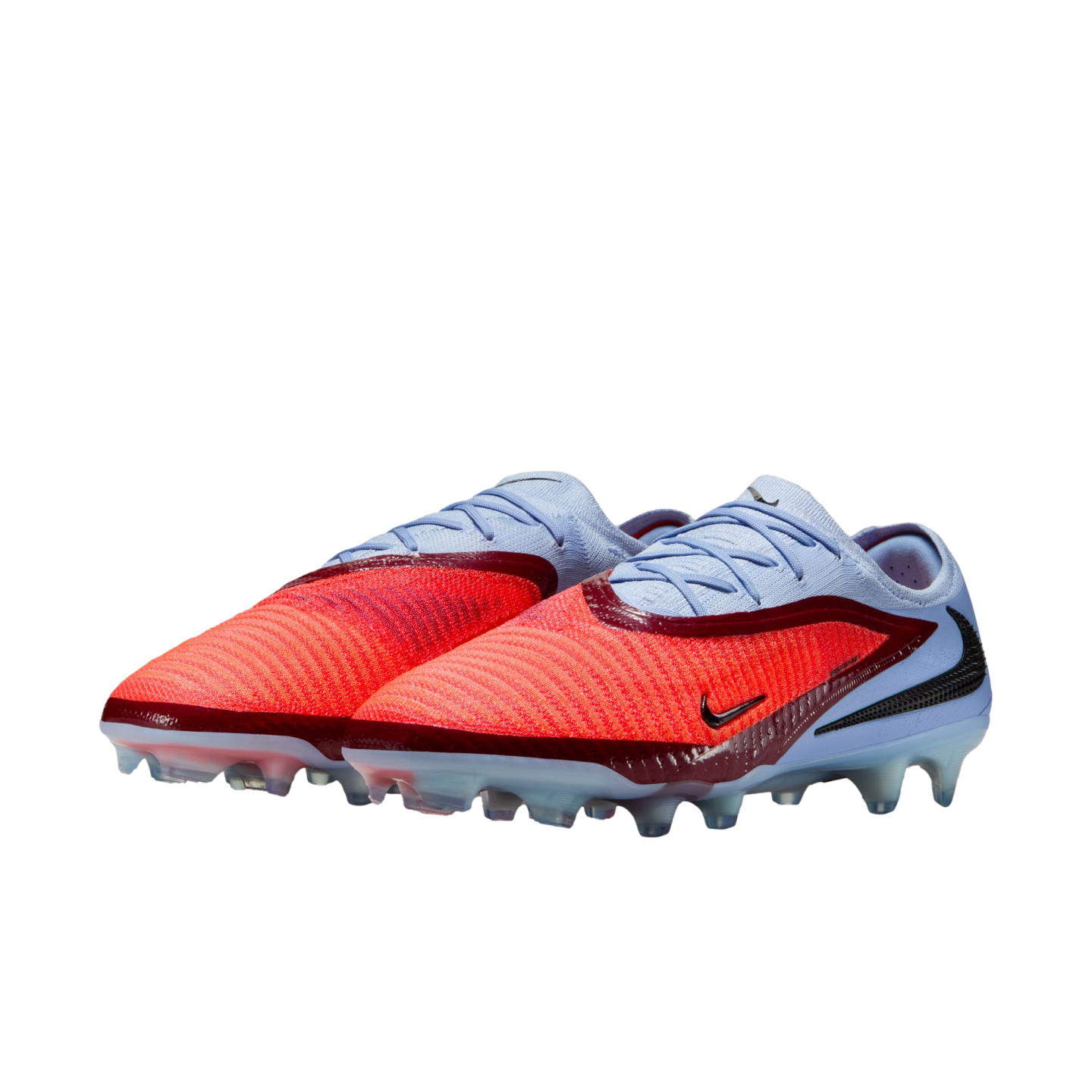 A pair of Nike soccer cleats with a vibrant orange textured forefoot, light blue heel, and maroon accents, isolated on a black background.