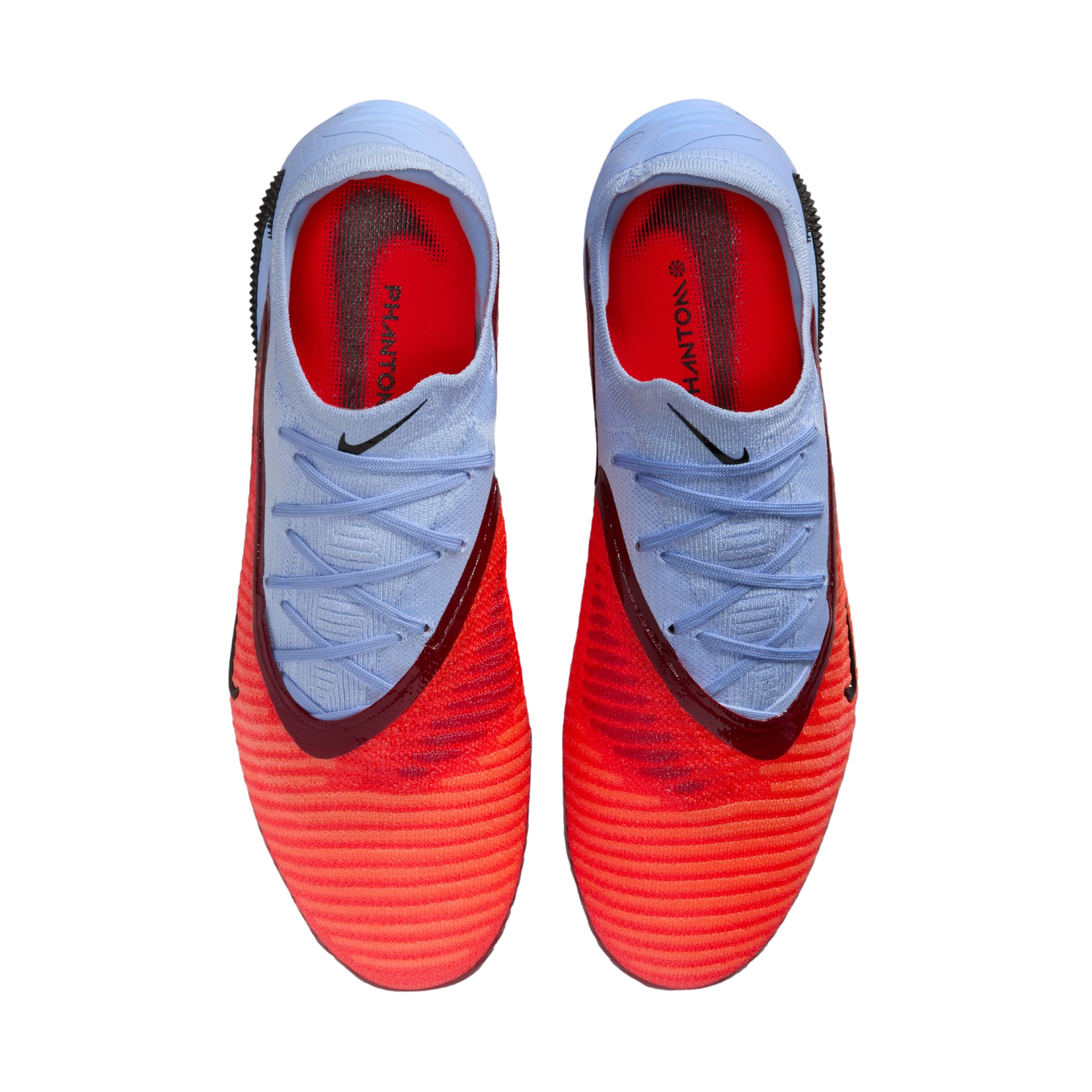 Top-down view of light blue and bright orange Nike Phantom soccer cleats with off-center lacing against a black background.