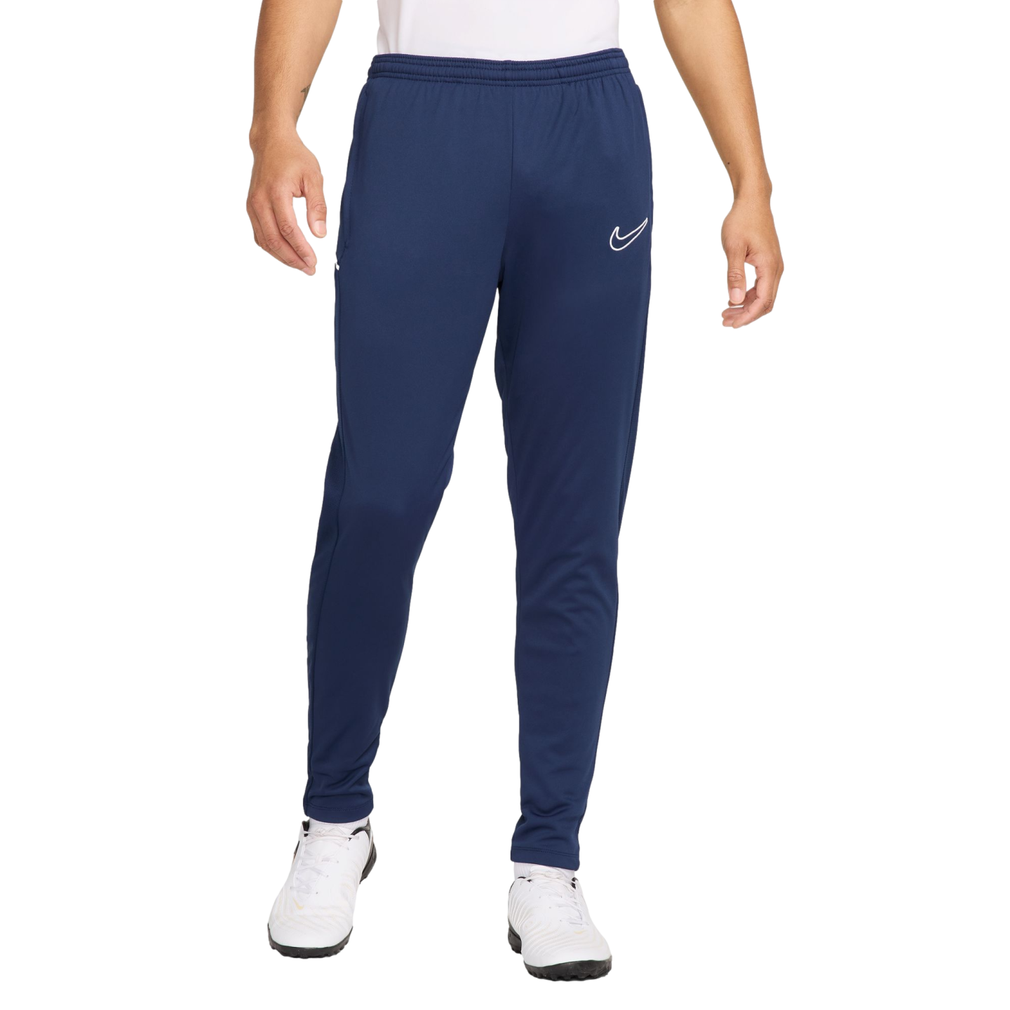 A person wearing navy blue Nike sweatpants with a white logo on the left leg and white athletic shoes.