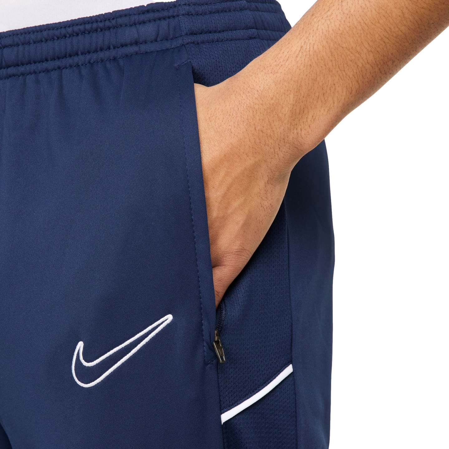 Close-up of a hand in the zippered pocket of navy blue Nike athletic shorts featuring a white swoosh logo.