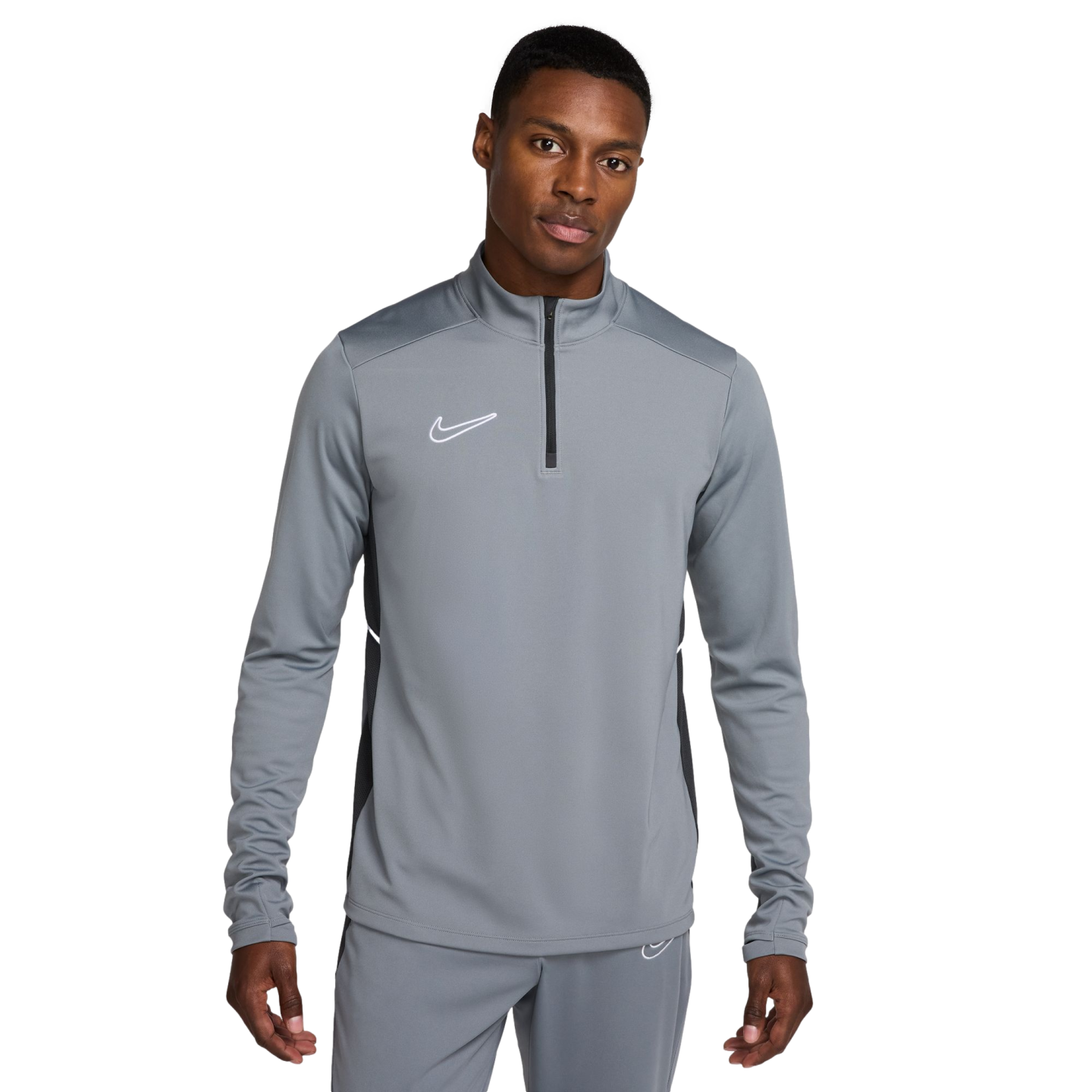 A man wearing a grey Nike half-zip long-sleeved athletic top and matching grey pants against a white background.