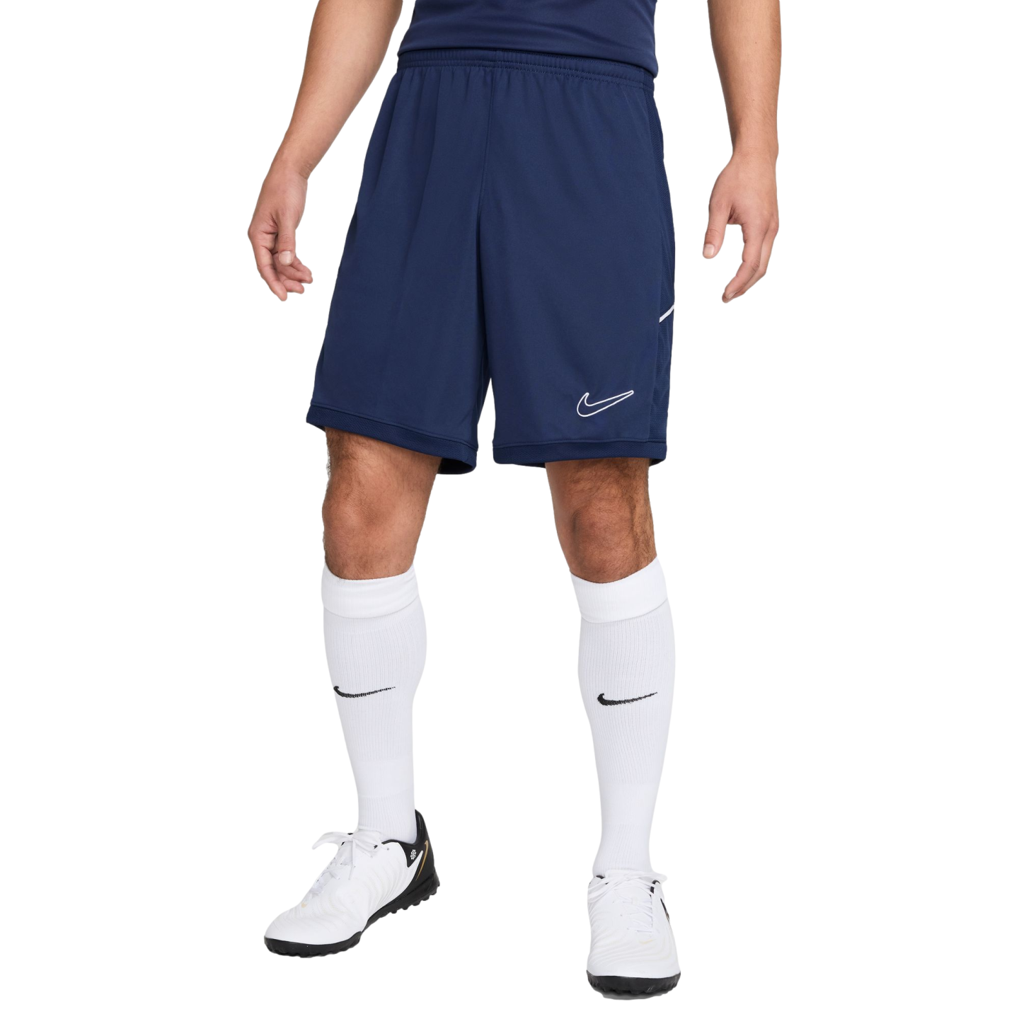 A person wearing navy blue Nike athletic shorts, white knee-high Nike socks, and white Nike athletic shoes against a plain white background.