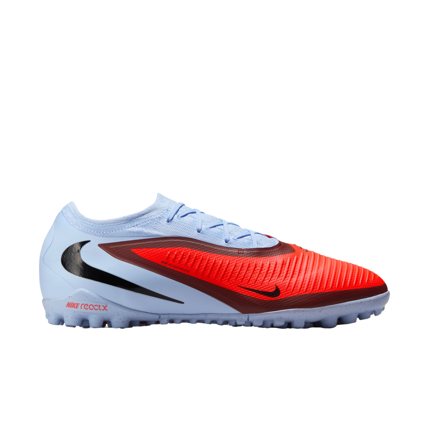 A side profile of a Nike turf soccer shoe featuring a light blue and textured red upper, black swoosh, and a speckled light blue sole.