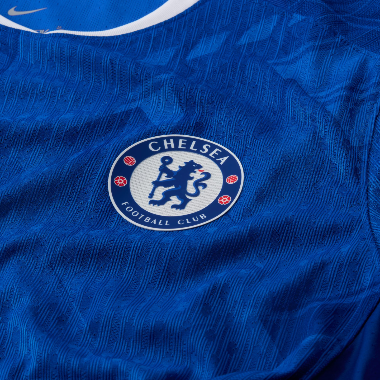 Close-up of a blue Chelsea FC jersey featuring the club's circular crest in the center and a textured fabric pattern.
