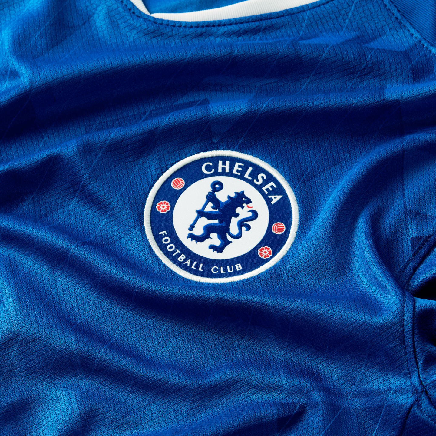 Close-up of a blue Chelsea Football Club jersey featuring the team's circular crest with a blue lion in the center.