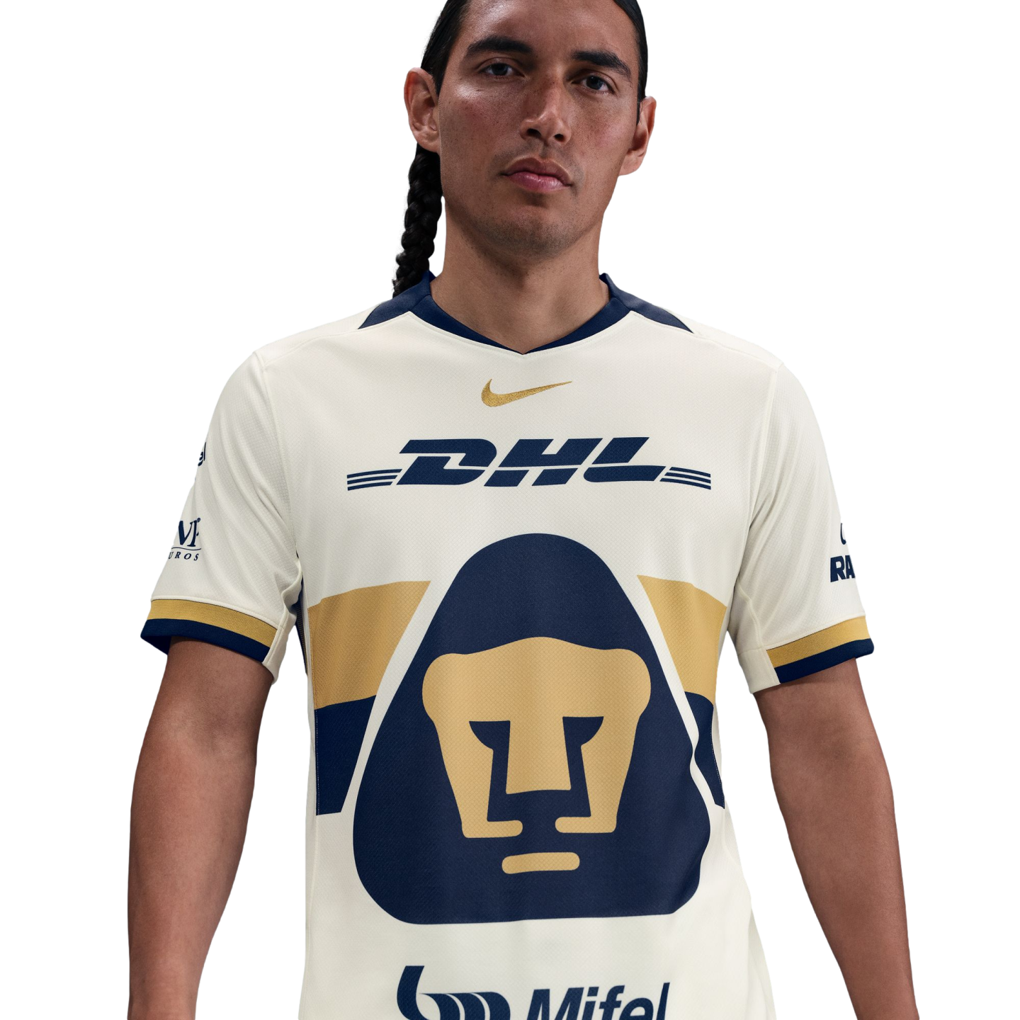 A man with long braided hair wearing a cream-colored Pumas soccer jersey with navy and gold details, featuring a large puma logo and DHL sponsorship.