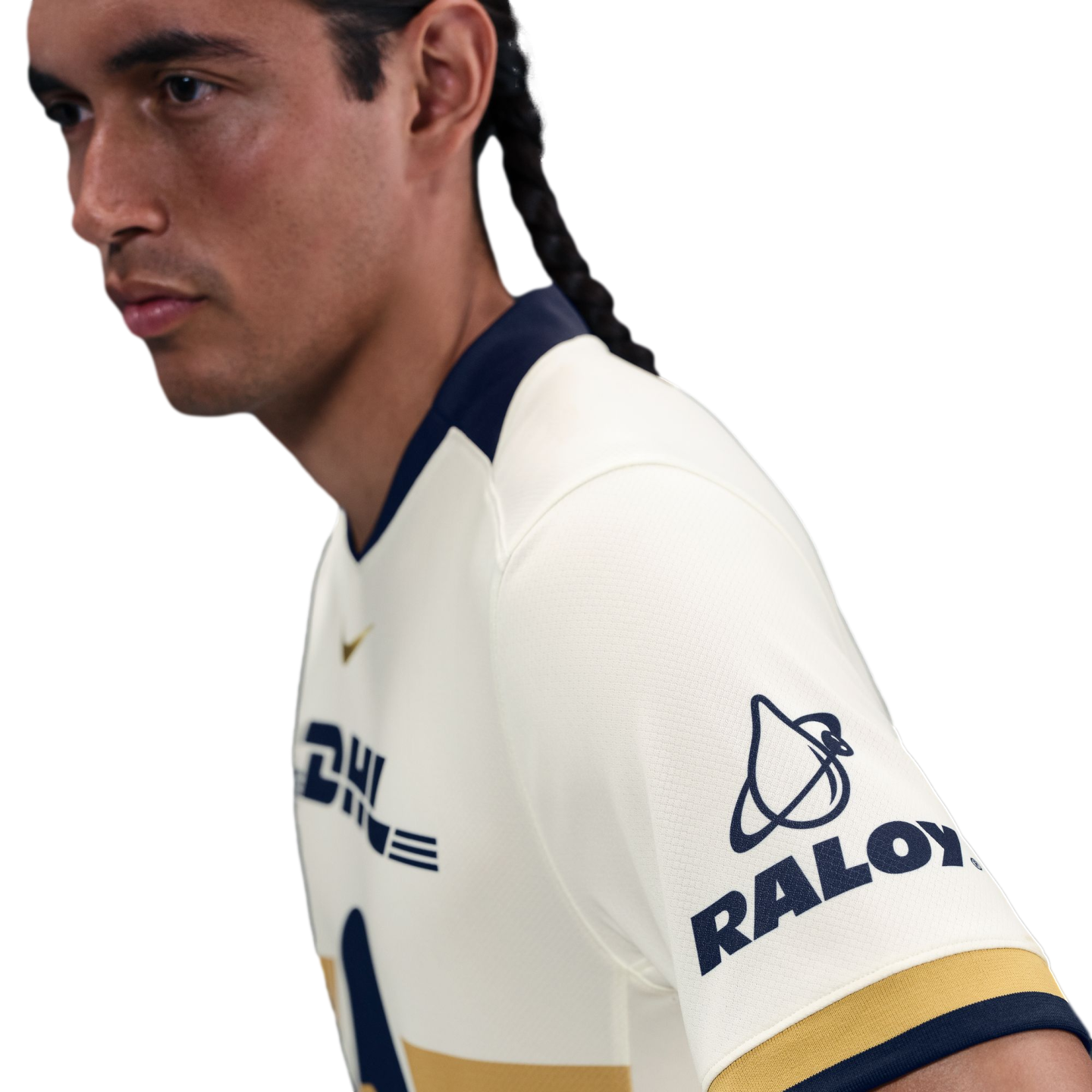 Side profile of a man with braided hair wearing a white soccer jersey with navy blue trim and RALOY and DHL logos.