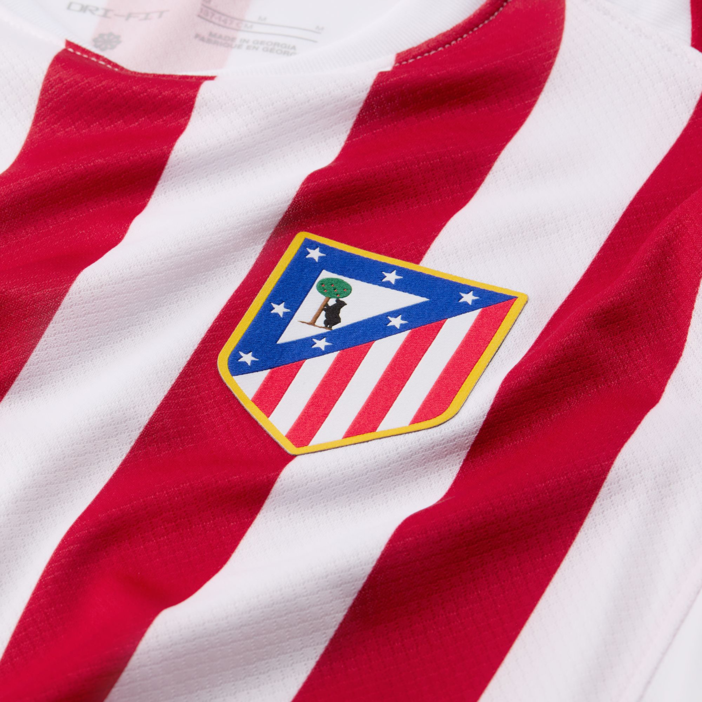 Close-up of a red and white striped football jersey featuring the Atlético Madrid club crest.