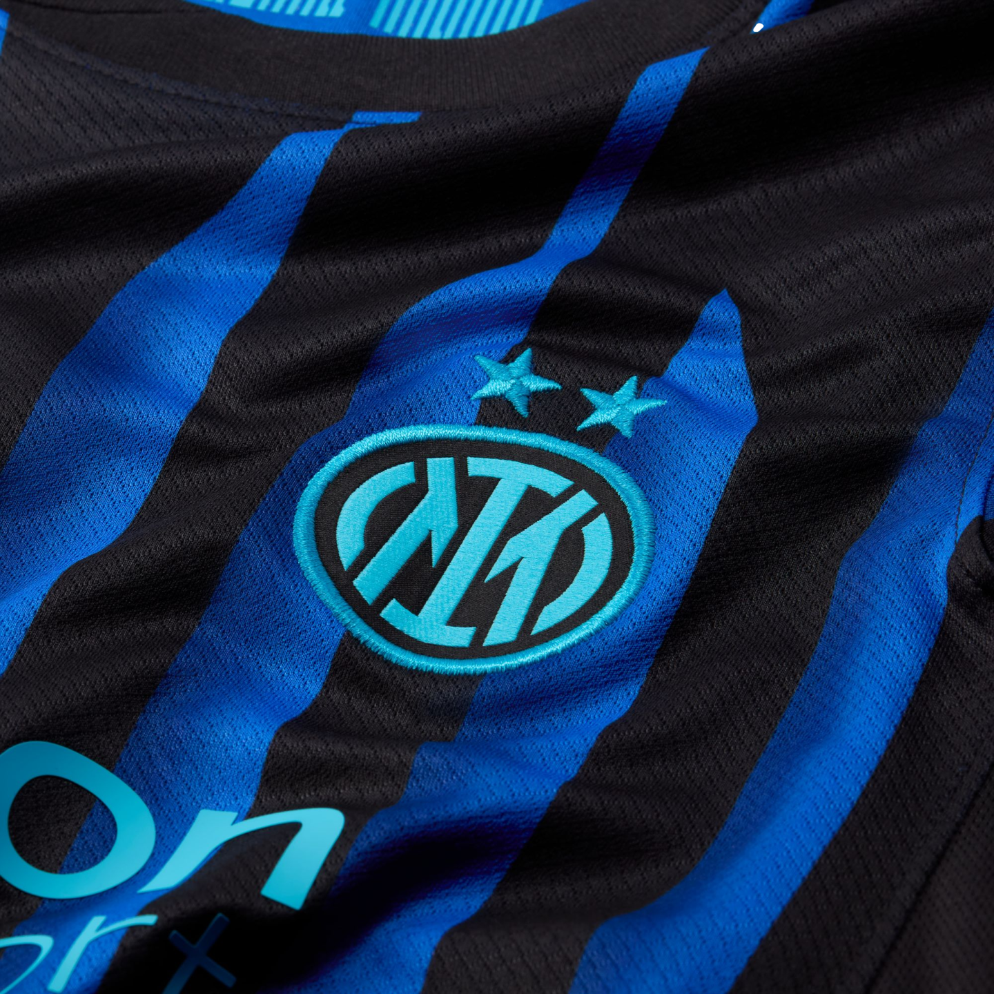 Close-up of a blue and black striped football jersey with the Inter Milan logo and two stars embroidered in light blue.
