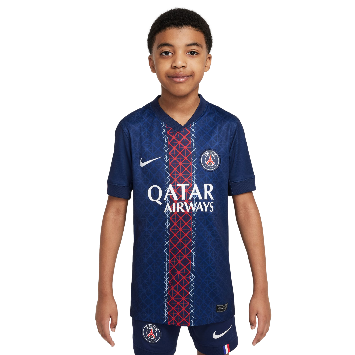 A young boy models a blue Paris Saint-Germain soccer jersey with a red central stripe and matching shorts against a white background. The kit features the club crest and Nike logo.