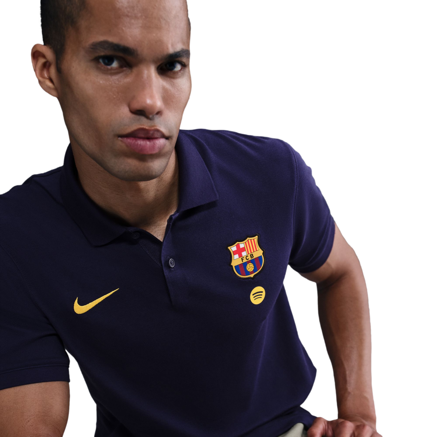 A man in a navy blue Nike FC Barcelona polo shirt featuring the club crest and yellow Spotify logo against a black background.
