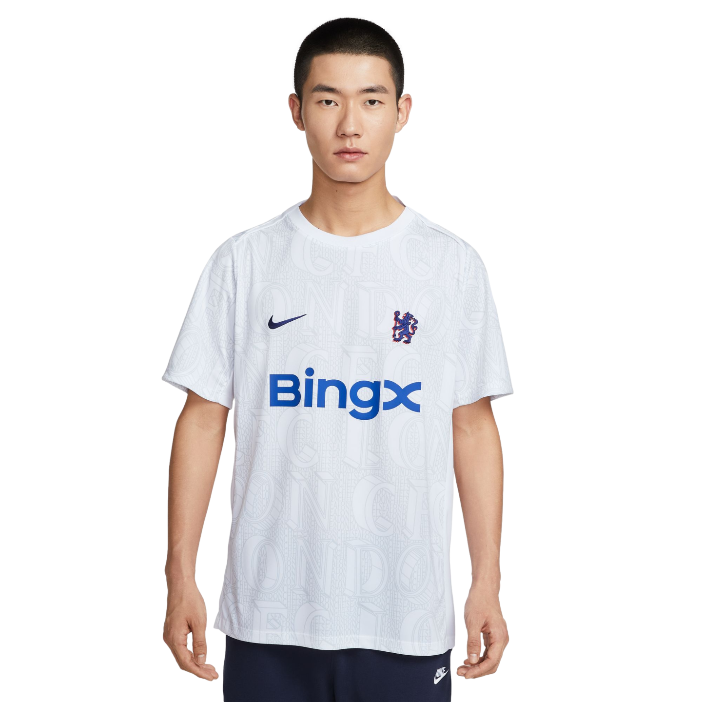 A man models a white Nike Chelsea FC t-shirt with a blue BingX logo and faint graphic pattern, set against a plain white background.