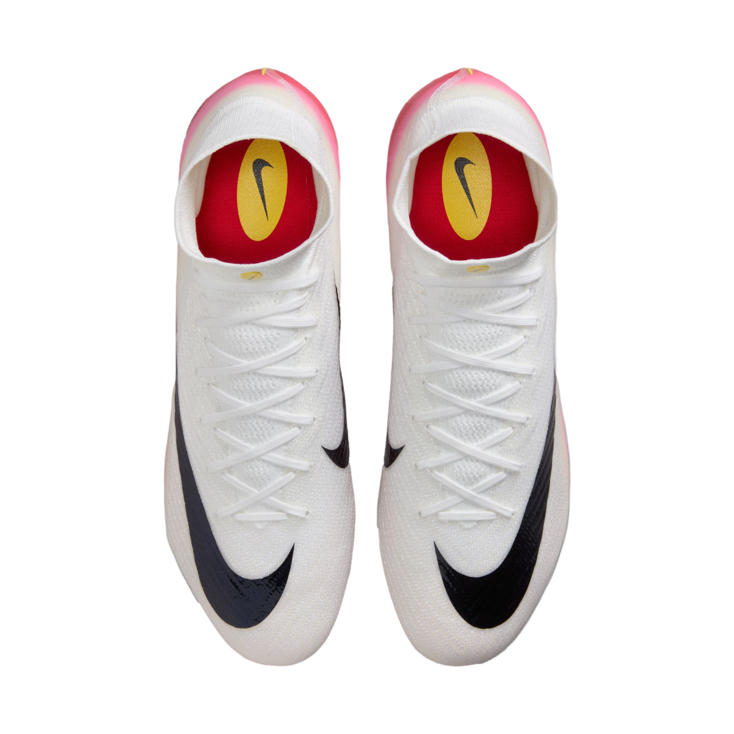 Top-down view of white Nike soccer cleats with black swooshes, red insoles, and pink-tinted heels against a black background.