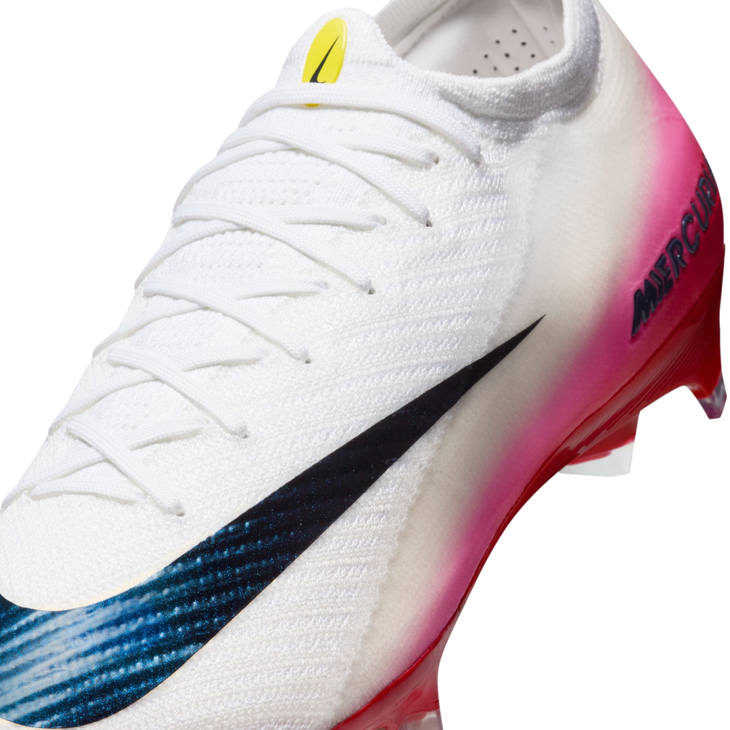 Close-up of a white Nike Mercurial soccer cleat featuring a pink gradient on the heel and a large black swoosh with a blue textured pattern.