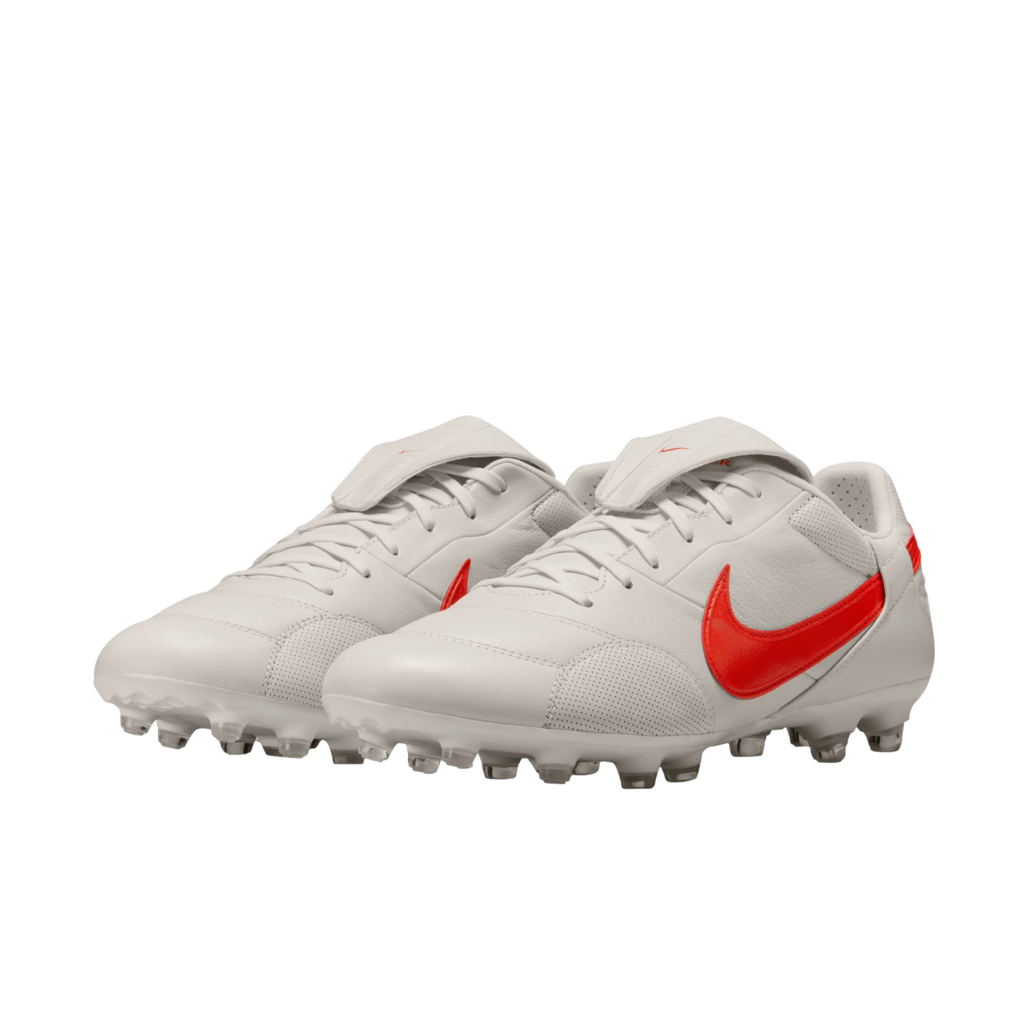 A pair of white Nike soccer cleats with bright red swoosh logos and fold-over tongues on a black background.