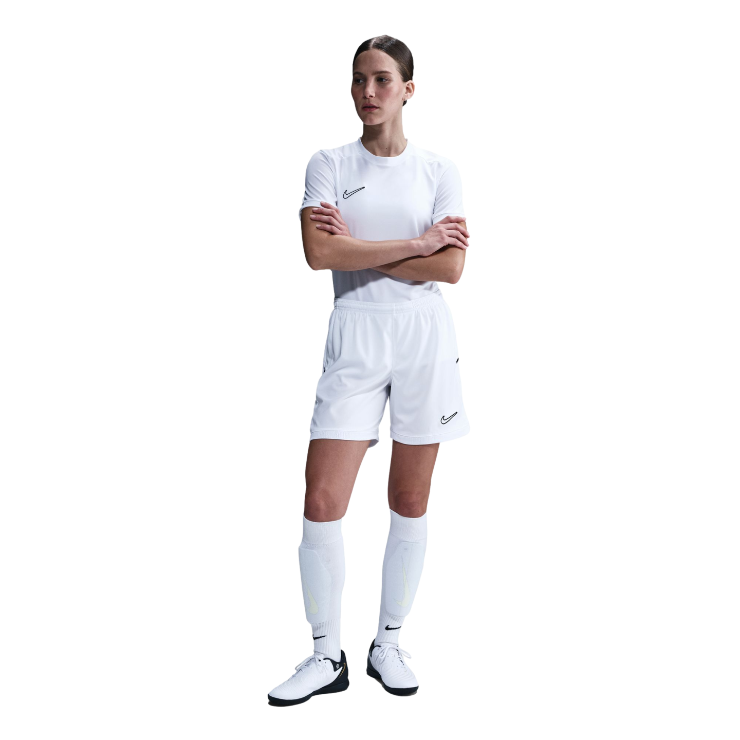 A woman in an all-white Nike soccer kit stands with her arms crossed against a plain white background.