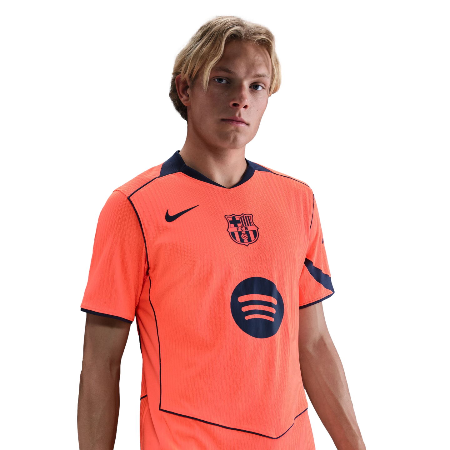 A young blonde man wearing a bright orange FC Barcelona soccer jersey with Nike and Spotify logos, set against a plain black background.