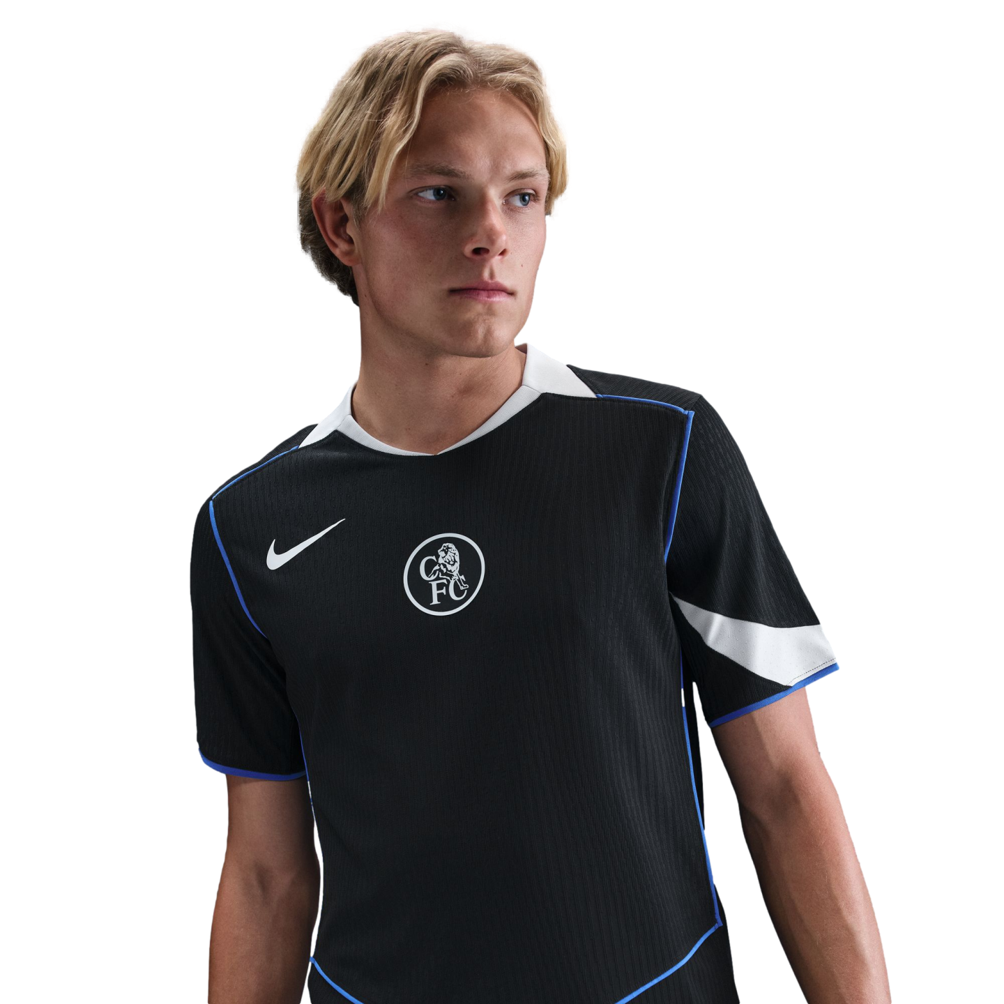 A young blonde man wearing a black Chelsea FC training shirt with blue and white accents against a black background.