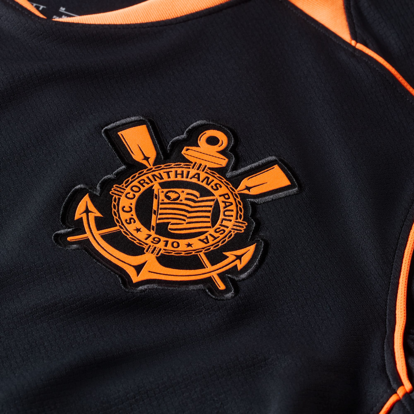 Close-up of the orange and black S.C. Corinthians Paulista crest embroidered on a black sports jersey.