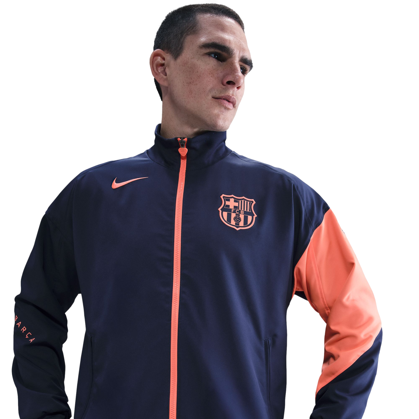 A man in a navy and orange Nike FC Barcelona track jacket against a black background.