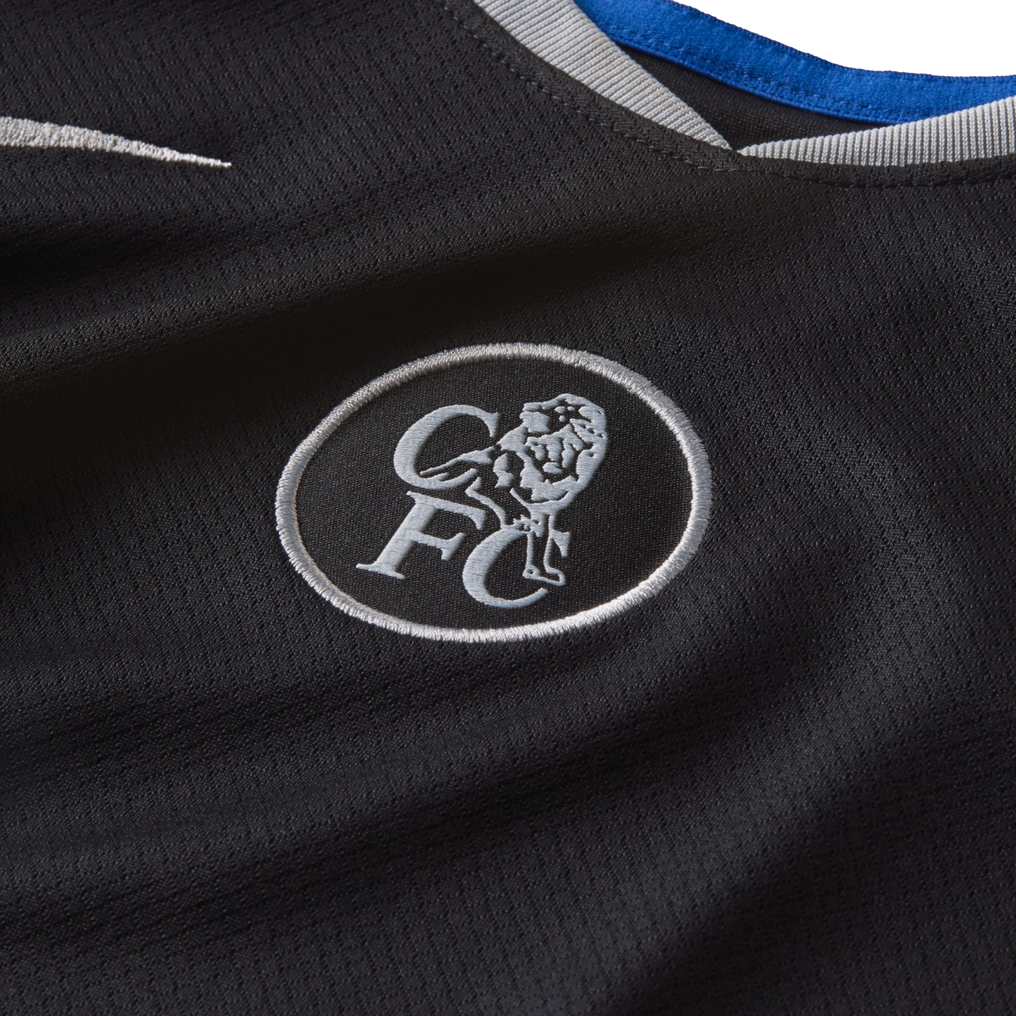 Close-up of a black Chelsea FC jersey featuring a silver embroidered crest with a lion and 'CFC' initials, a white Nike swoosh, and a collar with blue and grey trim.