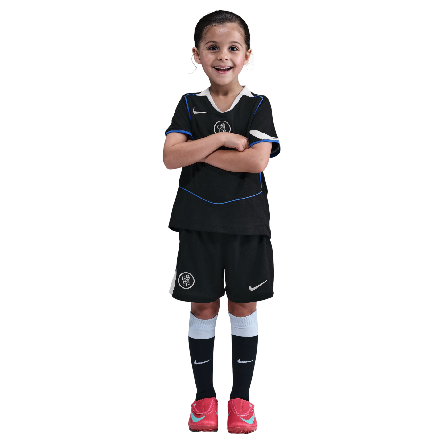 Young girl smiling with arms crossed, wearing a black Chelsea FC soccer kit and pink cleats against a solid black background.