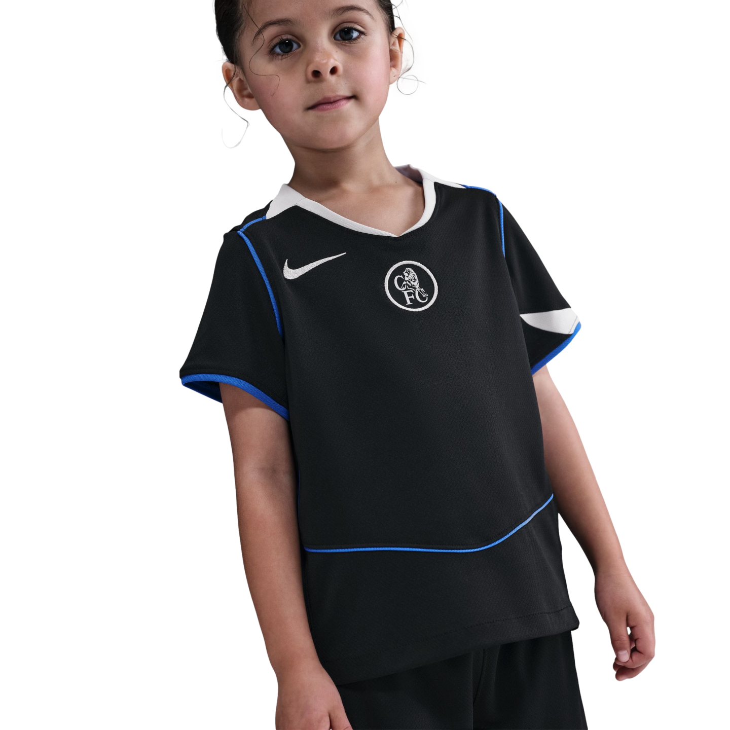A young child wearing a black Nike Chelsea FC football kit with blue and white trim, standing against a solid black background.